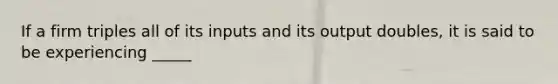 If a firm triples all of its inputs and its output doubles, it is said to be experiencing _____