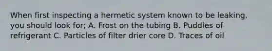 When first inspecting a hermetic system known to be leaking, you should look for; A. Frost on the tubing B. Puddles of refrigerant C. Particles of filter drier core D. Traces of oil