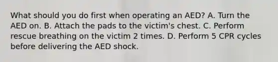 What should you do first when operating an AED? A. Turn the AED on. B. Attach the pads to the victim's chest. C. Perform rescue breathing on the victim 2 times. D. Perform 5 CPR cycles before delivering the AED shock.