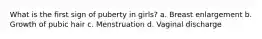 What is the first sign of puberty in girls? a. Breast enlargement b. Growth of pubic hair c. Menstruation d. Vaginal discharge