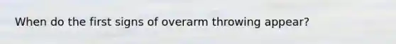 When do the first signs of overarm throwing appear?