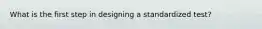 What is the first step in designing a standardized test?