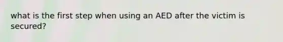 what is the first step when using an AED after the victim is secured?