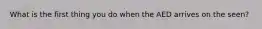 What is the first thing you do when the AED arrives on the seen?