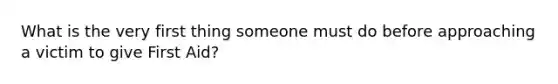 What is the very first thing someone must do before approaching a victim to give First Aid?