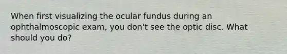 When first visualizing the ocular fundus during an ophthalmoscopic exam, you don't see the optic disc. What should you do?