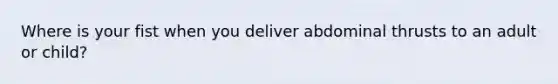 Where is your fist when you deliver abdominal thrusts to an adult or child?