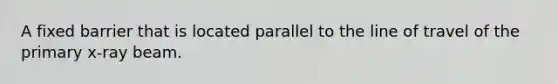 A fixed barrier that is located parallel to the line of travel of the primary x-ray beam.