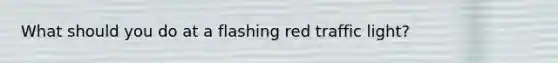 What should you do at a flashing red traffic light?