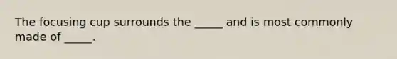 The focusing cup surrounds the _____ and is most commonly made of _____.