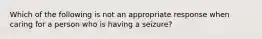 Which of the following is not an appropriate response when caring for a person who is having a seizure?