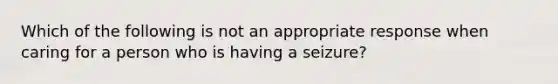 Which of the following is not an appropriate response when caring for a person who is having a seizure?