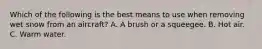 Which of the following is the best means to use when removing wet snow from an aircraft? A. A brush or a squeegee. B. Hot air. C. Warm water.