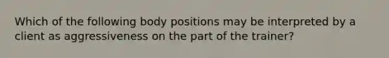 Which of the following body positions may be interpreted by a client as aggressiveness on the part of the trainer?