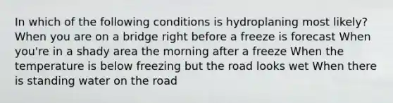 In which of the following conditions is hydroplaning most likely? When you are on a bridge right before a freeze is forecast When you're in a shady area the morning after a freeze When the temperature is below freezing but the road looks wet When there is standing water on the road