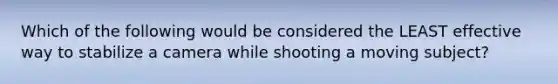 Which of the following would be considered the LEAST effective way to stabilize a camera while shooting a moving subject?