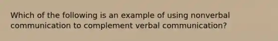 Which of the following is an example of using nonverbal communication to complement verbal communication?