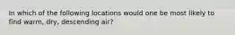 In which of the following locations would one be most likely to find warm, dry, descending air?