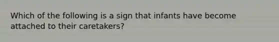 Which of the following is a sign that infants have become attached to their caretakers?