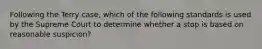 Following the Terry case, which of the following standards is used by the Supreme Court to determine whether a stop is based on reasonable suspicion?