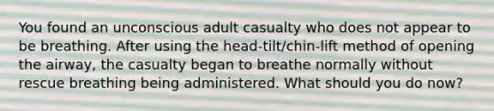 You found an unconscious adult casualty who does not appear to be breathing. After using the head-tilt/chin-lift method of opening the airway, the casualty began to breathe normally without rescue breathing being administered. What should you do now?