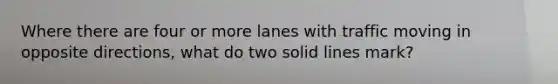 Where there are four or more lanes with traffic moving in opposite directions, what do two solid lines mark?