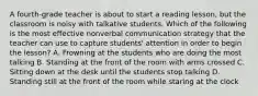 A fourth-grade teacher is about to start a reading lesson, but the classroom is noisy with talkative students. Which of the following is the most effective nonverbal communication strategy that the teacher can use to capture students' attention in order to begin the lesson? A. Frowning at the students who are doing the most talking B. Standing at the front of the room with arms crossed C. Sitting down at the desk until the students stop talking D. Standing still at the front of the room while staring at the clock