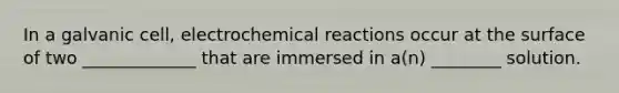 In a galvanic cell, electrochemical reactions occur at the surface of two _____________ that are immersed in a(n) ________ solution.