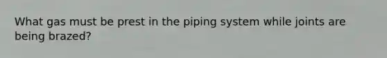 What gas must be prest in the piping system while joints are being brazed?