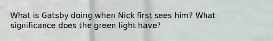 What is Gatsby doing when Nick first sees him? What significance does the green light have?