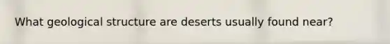 What geological structure are deserts usually found near?