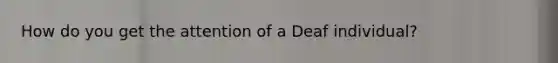 How do you get the attention of a Deaf individual?