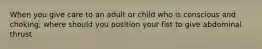 When you give care to an adult or child who is conscious and choking, where should you position your fist to give abdominal thrust