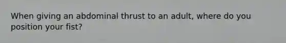 When giving an abdominal thrust to an adult, where do you position your fist?