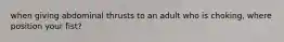 when giving abdominal thrusts to an adult who is choking, where position your fist?