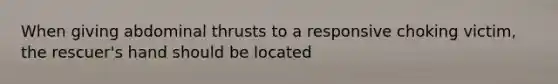 When giving abdominal thrusts to a responsive choking victim, the rescuer's hand should be located