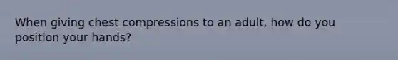 When giving chest compressions to an adult, how do you position your hands?