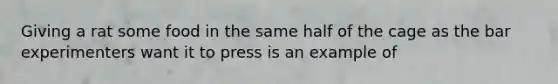 Giving a rat some food in the same half of the cage as the bar experimenters want it to press is an example of