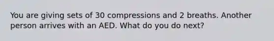 You are giving sets of 30 compressions and 2 breaths. Another person arrives with an AED. What do you do next?