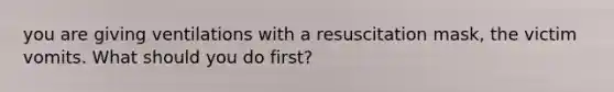 you are giving ventilations with a resuscitation mask, the victim vomits. What should you do first?