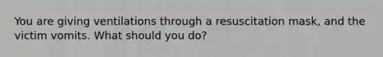 You are giving ventilations through a resuscitation mask, and the victim vomits. What should you do?