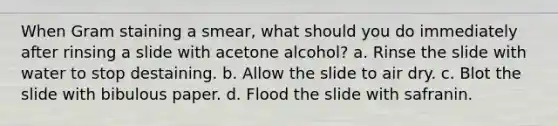 When Gram staining a smear, what should you do immediately after rinsing a slide with acetone alcohol? a. Rinse the slide with water to stop destaining. b. Allow the slide to air dry. c. Blot the slide with bibulous paper. d. Flood the slide with safranin.