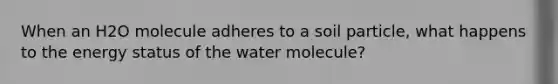 When an H2O molecule adheres to a soil particle, what happens to the energy status of the water molecule?