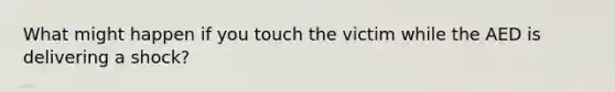 What might happen if you touch the victim while the AED is delivering a shock?