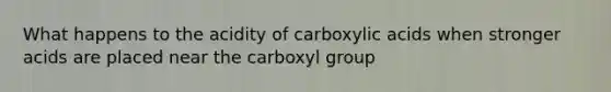 What happens to the acidity of carboxylic acids when stronger acids are placed near the carboxyl group