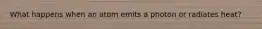 What happens when an atom emits a photon or radiates heat?