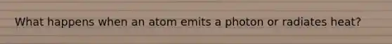 What happens when an atom emits a photon or radiates heat?