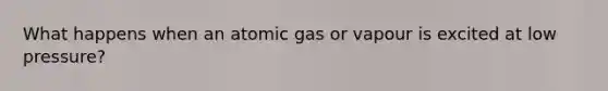 What happens when an atomic gas or vapour is excited at low pressure?