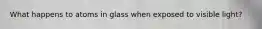 What happens to atoms in glass when exposed to visible light?