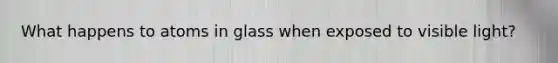 What happens to atoms in glass when exposed to visible light?